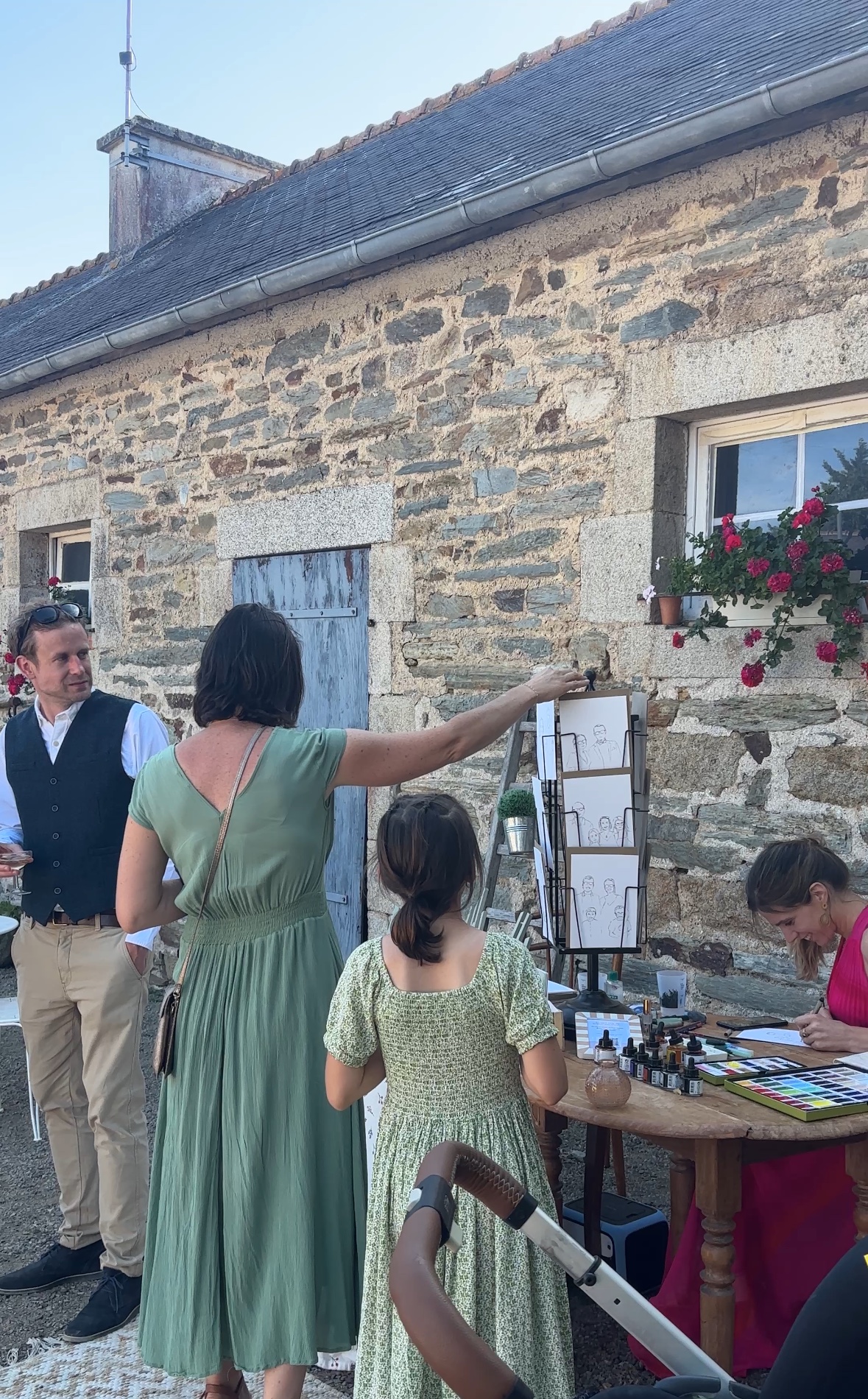 Des invités découvrent le stand de portraits pendant que Blanche dessine